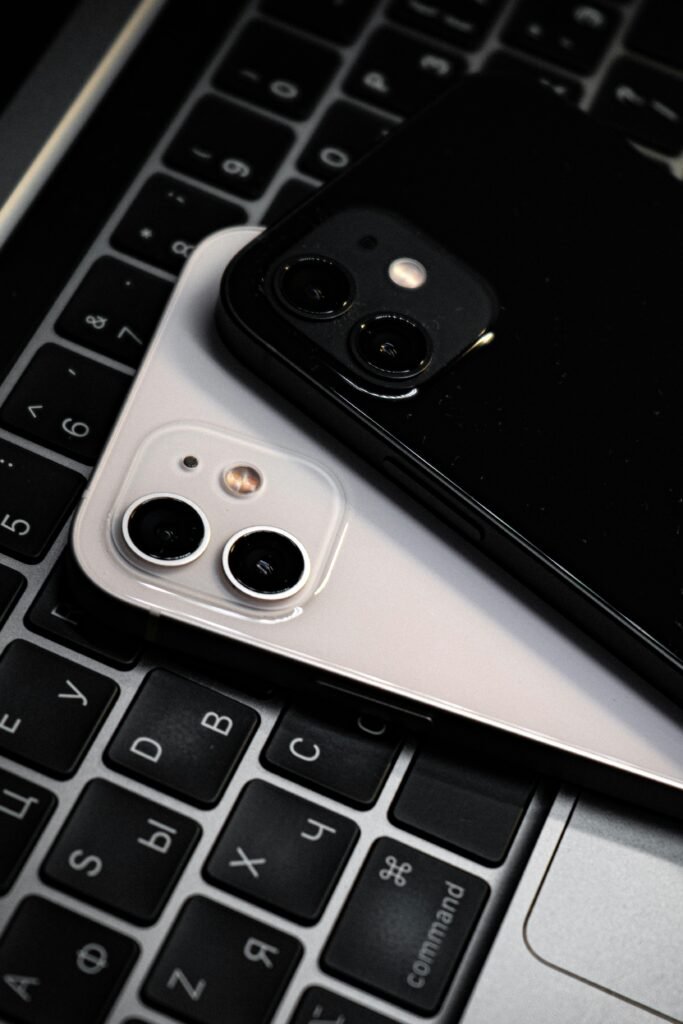 Two smartphones on a laptop keyboard, showcasing technology elegance in a vertical shot.
